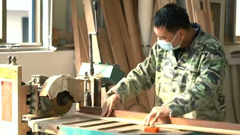 Worker cutting and shaping sauna wood parts in the CSauna workshop