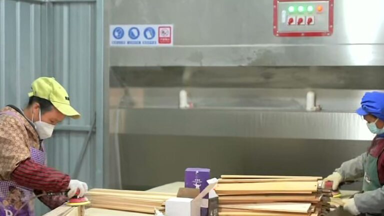 Workers sanding and preparing sauna wood parts in the workshop